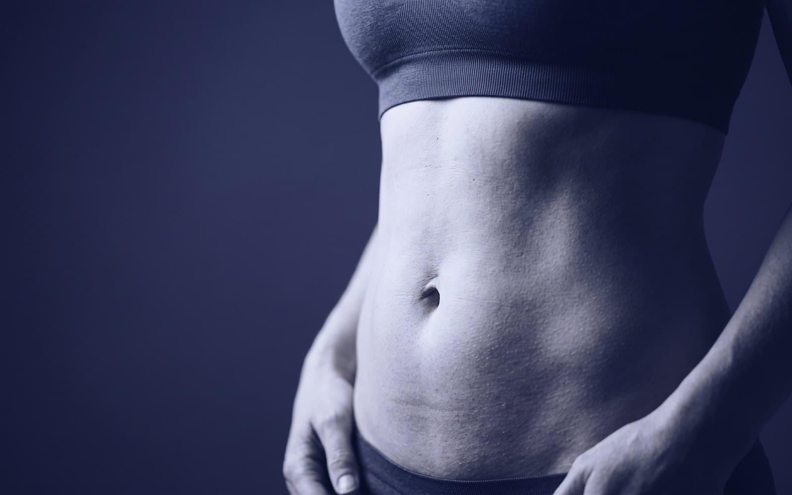 A woman's waist in a plain dark top, lit from the side